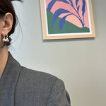 A woman wears gold hoop earrings with three small white pearls dangling from each.