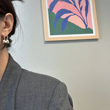 A woman wears gold hoop earrings with three small white pearls dangling from each.