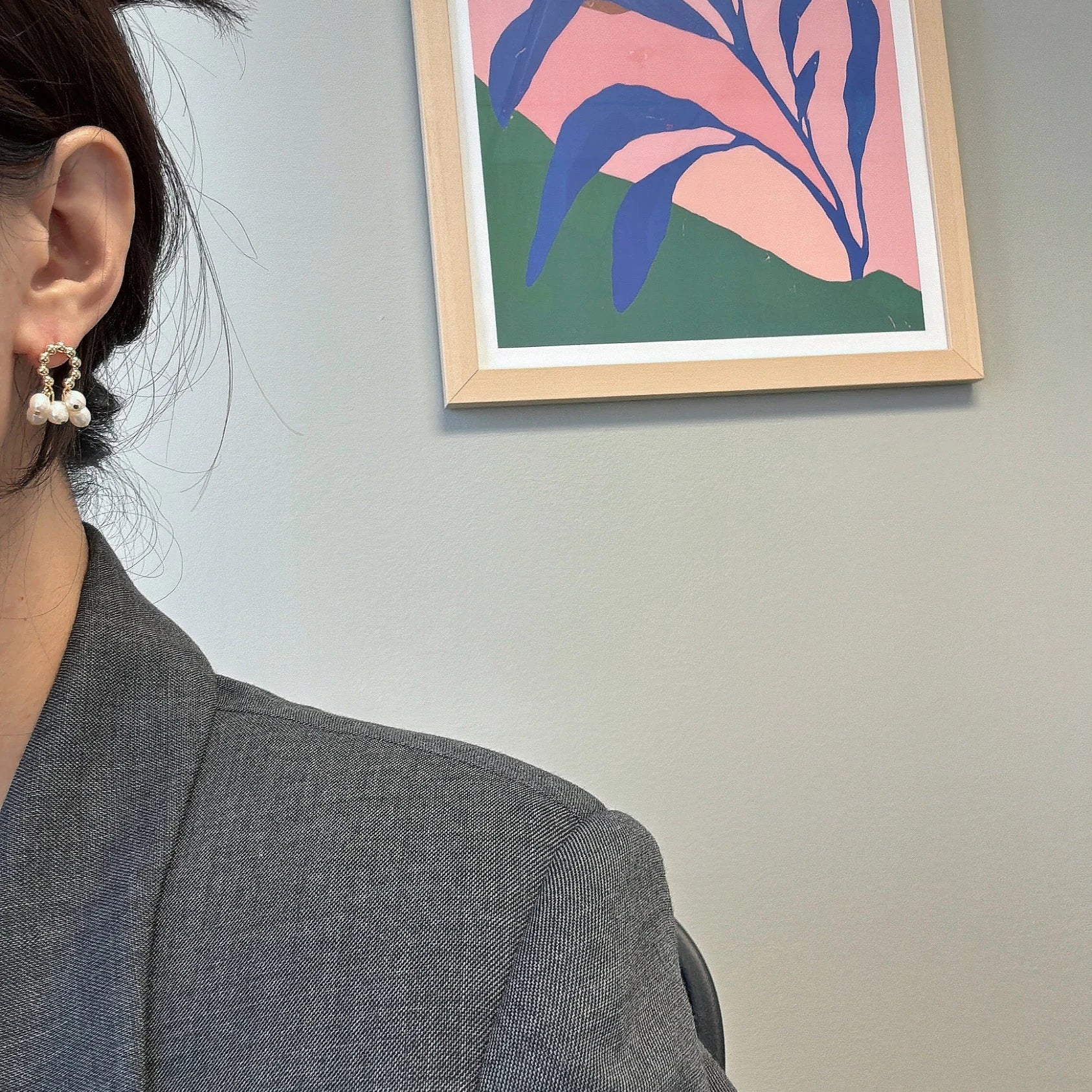 A woman wears gold hoop earrings with three small white pearls dangling from each.