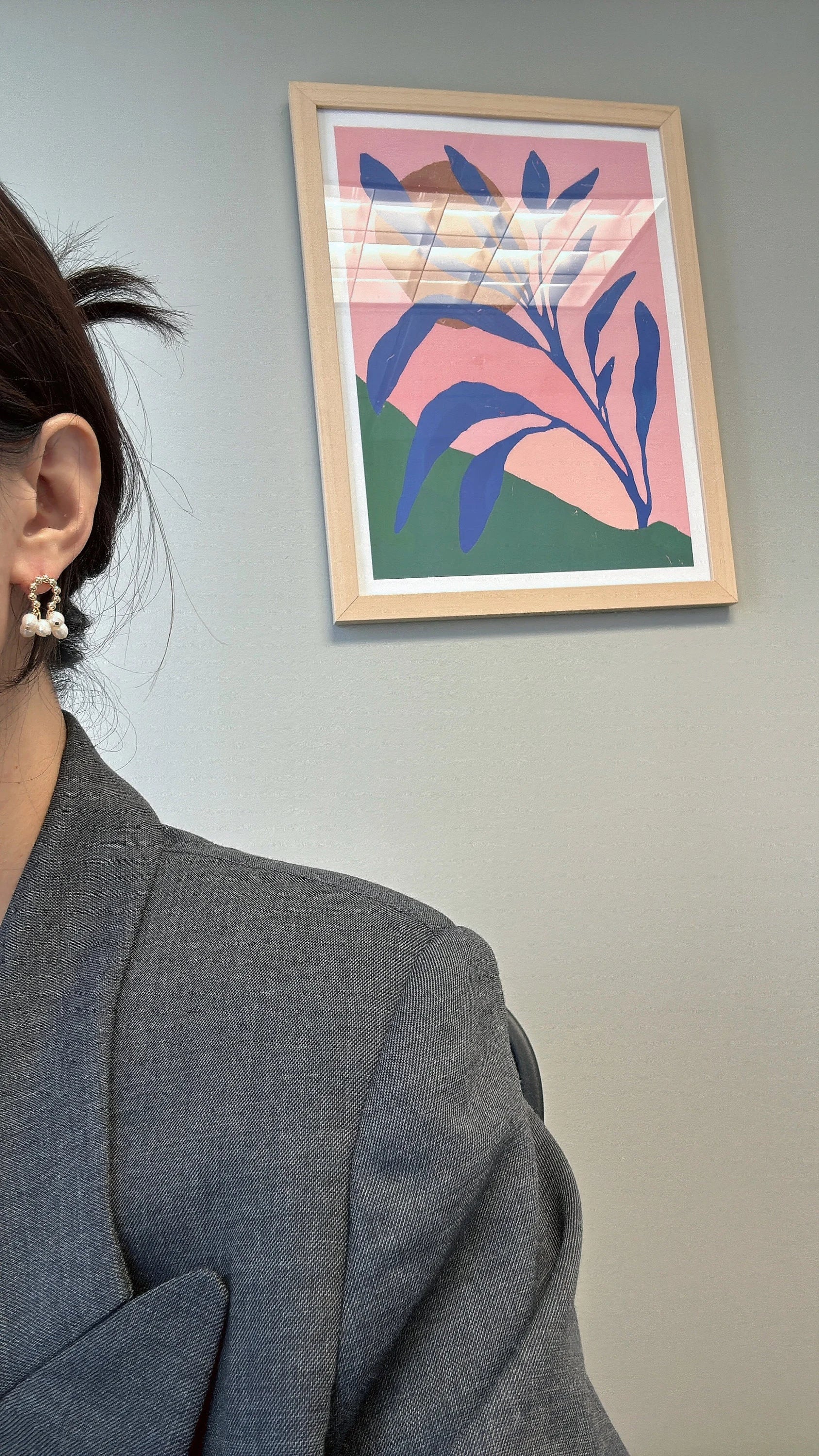 A woman wears gold hoop earrings with three small white pearls dangling from each.