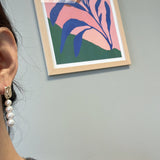 A person wears a gold and pearl earring with four pearls.