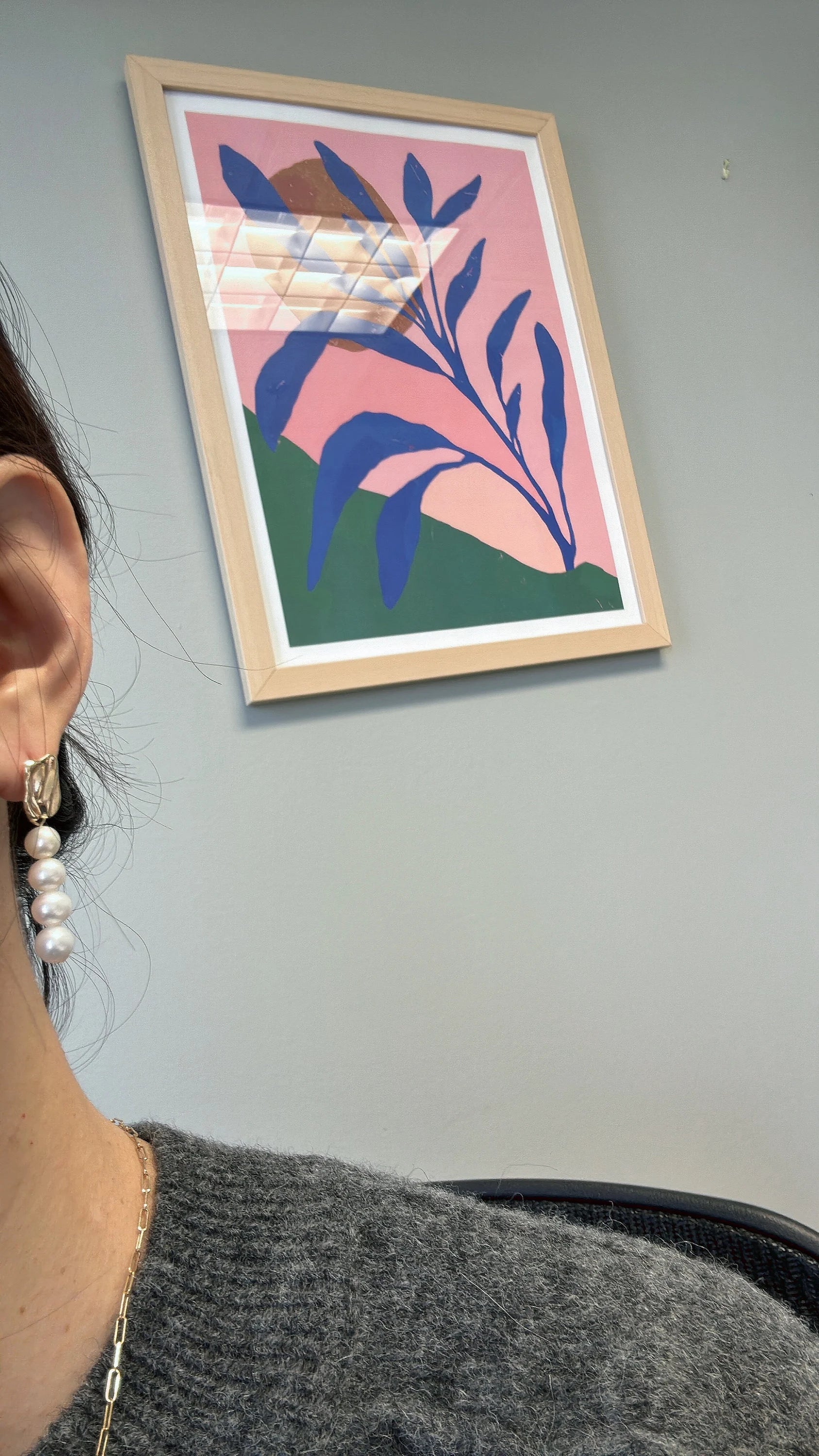 A person wears a gold and pearl earring with four pearls.