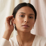 A model wears Caellia 14K gold hoop earrings featuring three small freshwater pearls.