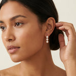A model wears Caellia 14K gold drop earrings featuring three vertical freshwater pearls.