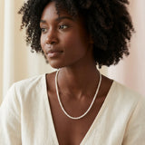 A woman wearing a delicate Caellia 14K gold tiny freshwater pearl necklace.