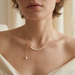 A model wears the Caellia 14K gold adjustable necklace featuring a row of rice freshwater pearls.