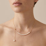 A model wears the Caellia 14K gold adjustable necklace featuring a row of rice freshwater pearls.