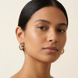 A model wears Caellia silver-plated hoop earrings featuring suspended freshwater pearls.