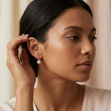 A model wears Caellia 14K gold plated sterling silver freshwater pearl dangle earrings.