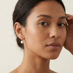A model wears Caellia 14K gold plated sterling silver freshwater pearl dangle earrings.