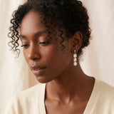 A model wears Caellia 14K gold plated sterling silver earrings featuring three pearl drops.