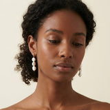 A model wears Caellia 14K gold plated sterling silver earrings featuring three pearl drops.