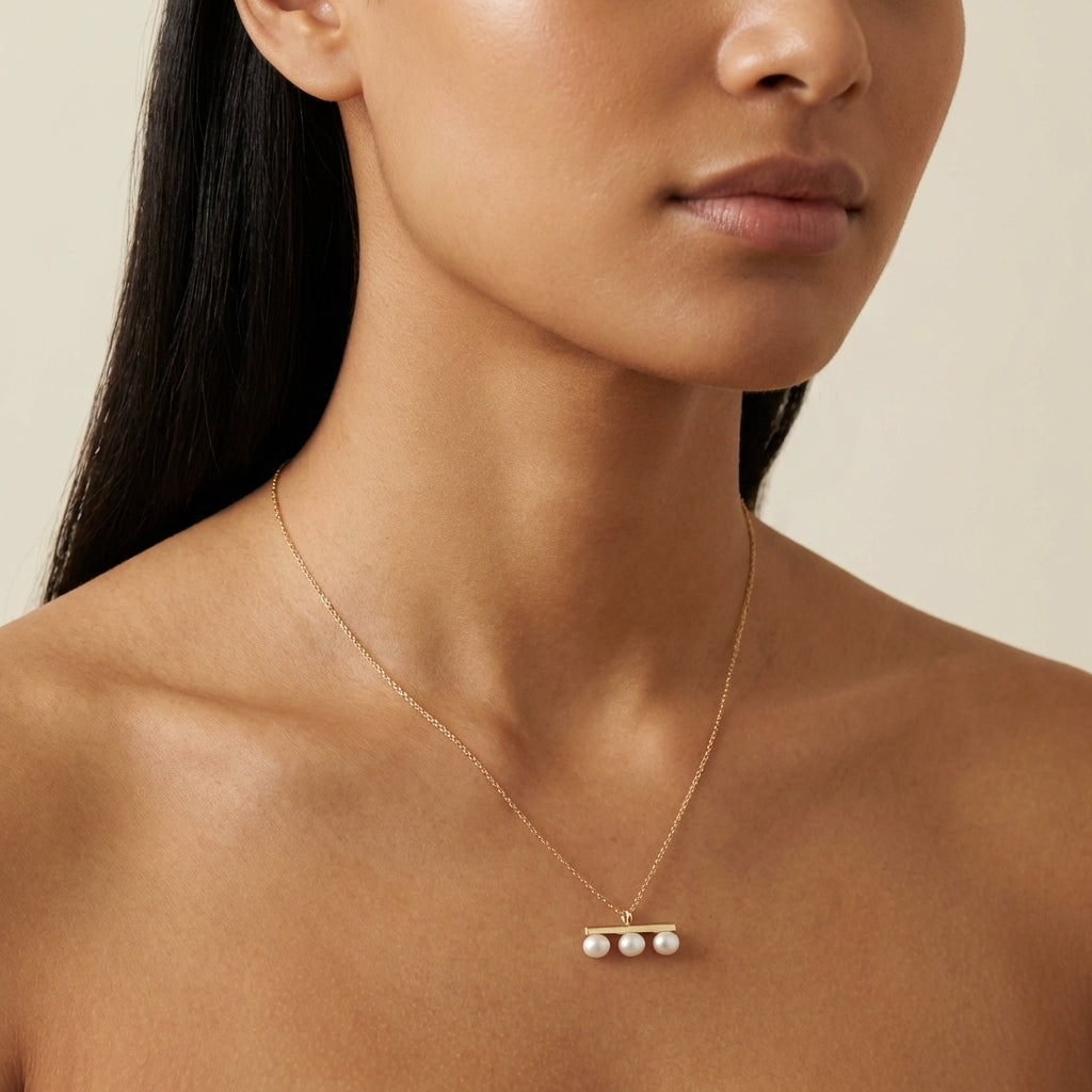 A model wears the Caellia 14K gold plated necklace featuring three freshwater pearls on a bar.