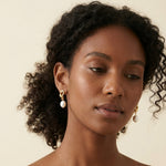 A model wears Caellia 14K gold twist knot earrings featuring lustrous freshwater pearls.