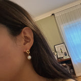 Twist drop pearl earrings with a gold knot design and white pearls.