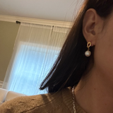 Twist drop pearl earrings with a gold knot and white pearl.