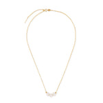 A gold chain necklace with three white pearls and two gold beads.