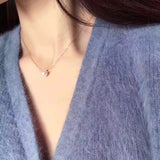A woman wears a gold chain necklace with a single, off-round freshwater pearl.
