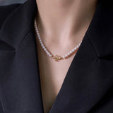 A woman wears a freshwater pearl necklace with an 18K gold clover clasp.