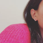 A woman wears three bead freshwater pearl earrings with a pink sweater.