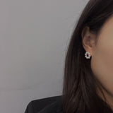 A woman wears a freshwater pearl flower stud earring on her right ear.