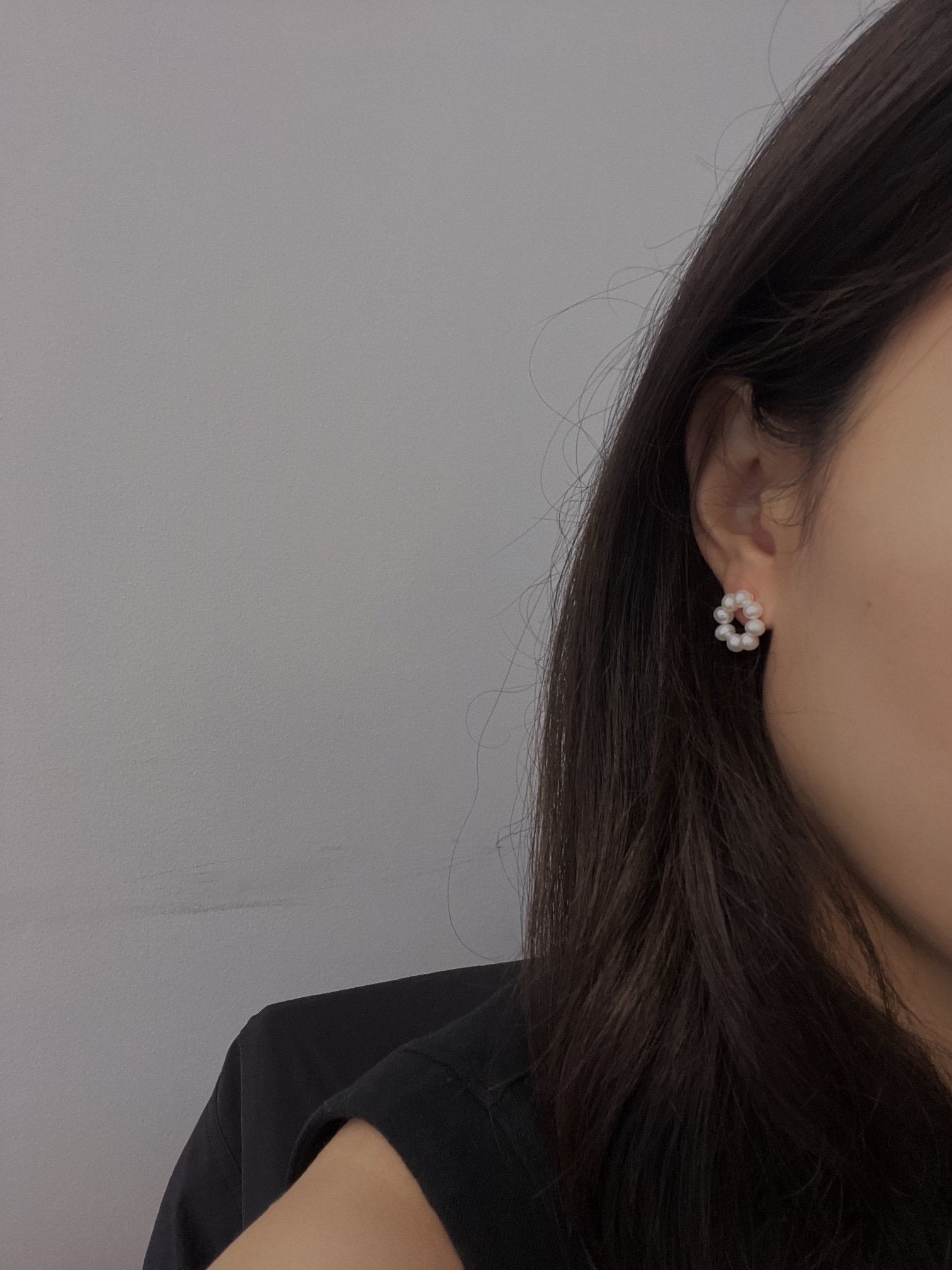 A woman wears a freshwater pearl flower stud earring on her right ear.