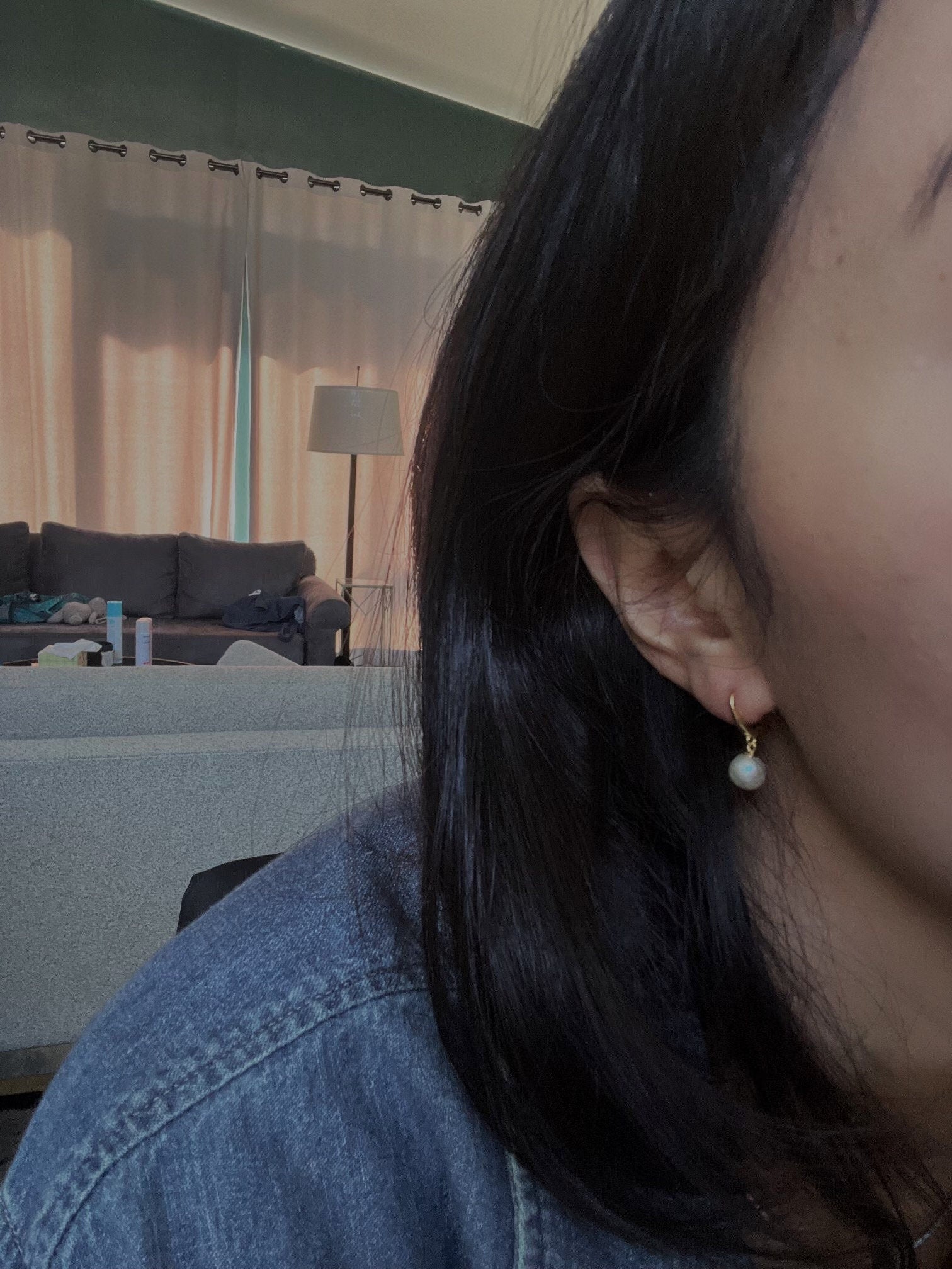 A close-up of a person wearing a single pearl hoop earring.