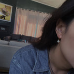 Pearl hoop earrings featuring a single white pearl on a gold-toned hoop.