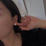 Large white pearl stud earrings on a woman's ear.