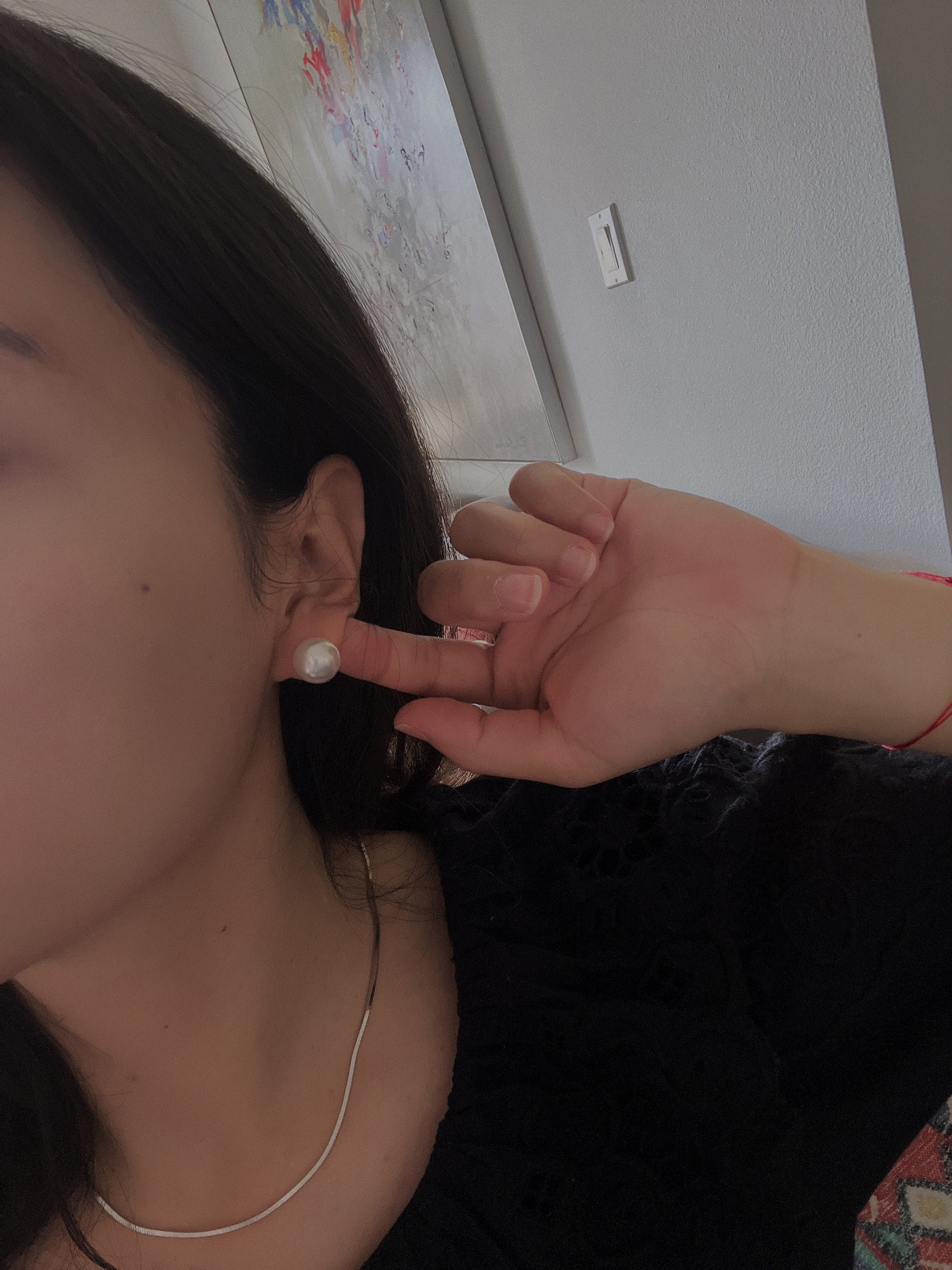 Large white pearl stud earrings on a woman's ear.