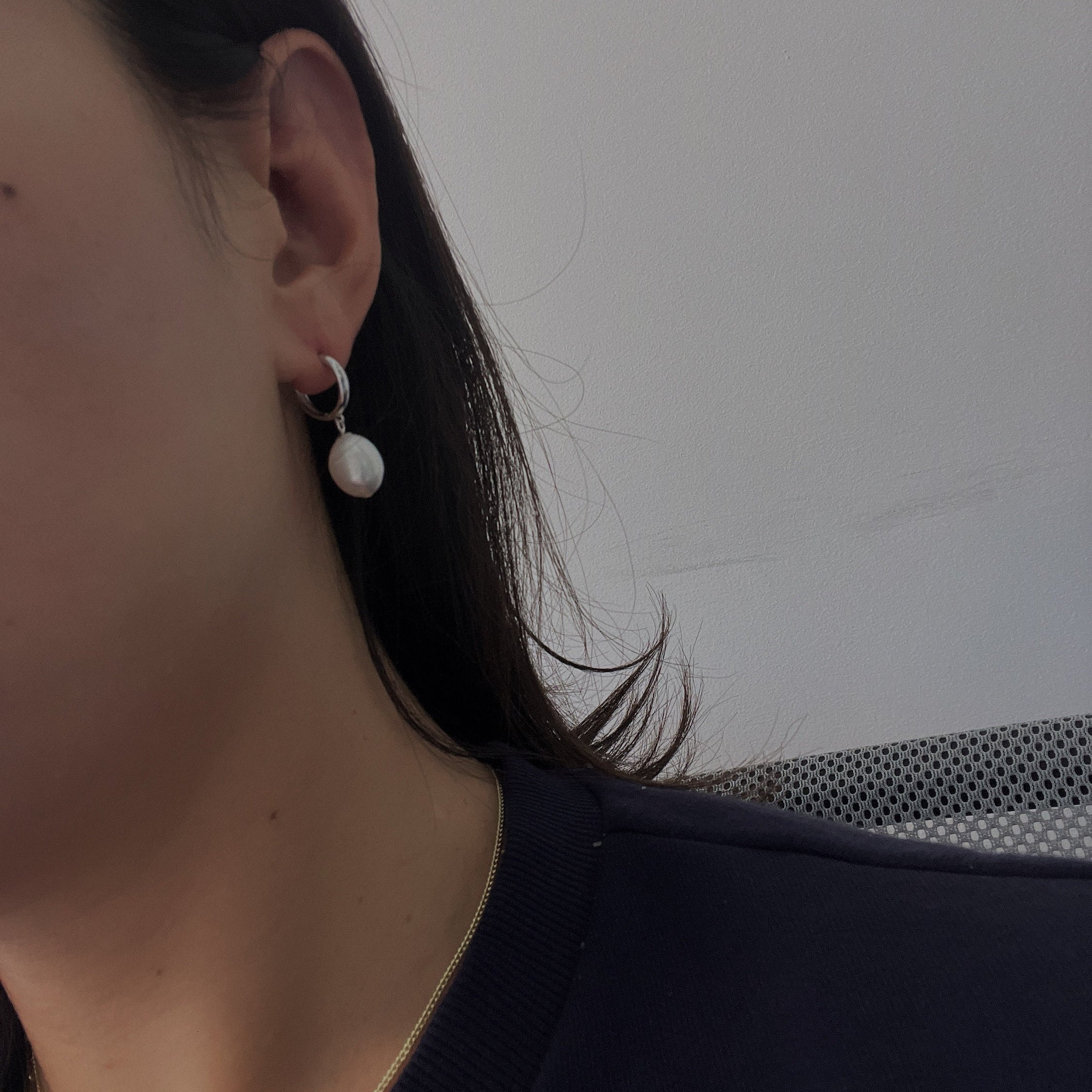 Freshwater pearl dewdrop earrings on a person's ear.