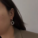 Freshwater pearl circular ring dangling earrings on a person's ear.