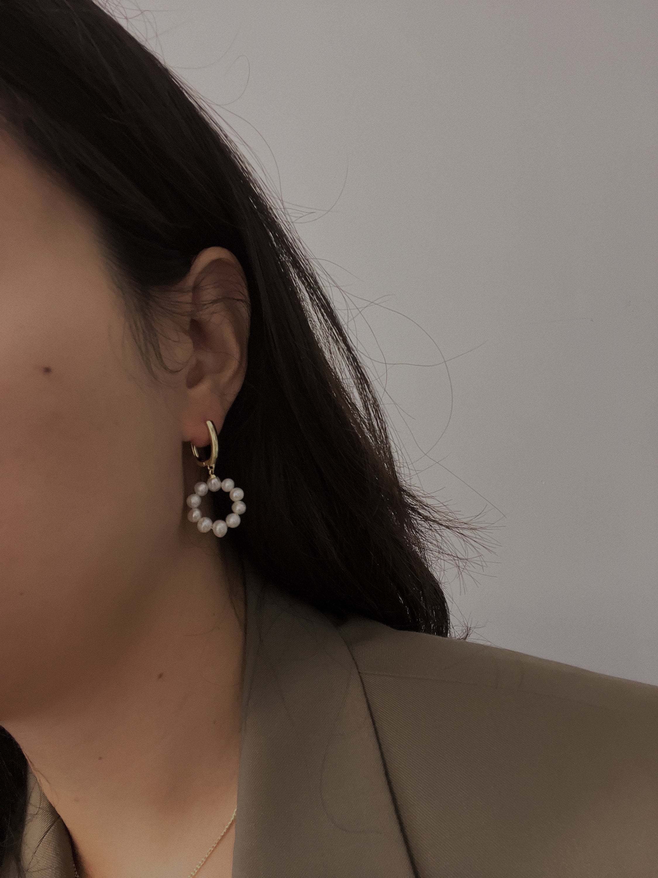 Freshwater pearl circular ring dangling earrings on a person's ear.