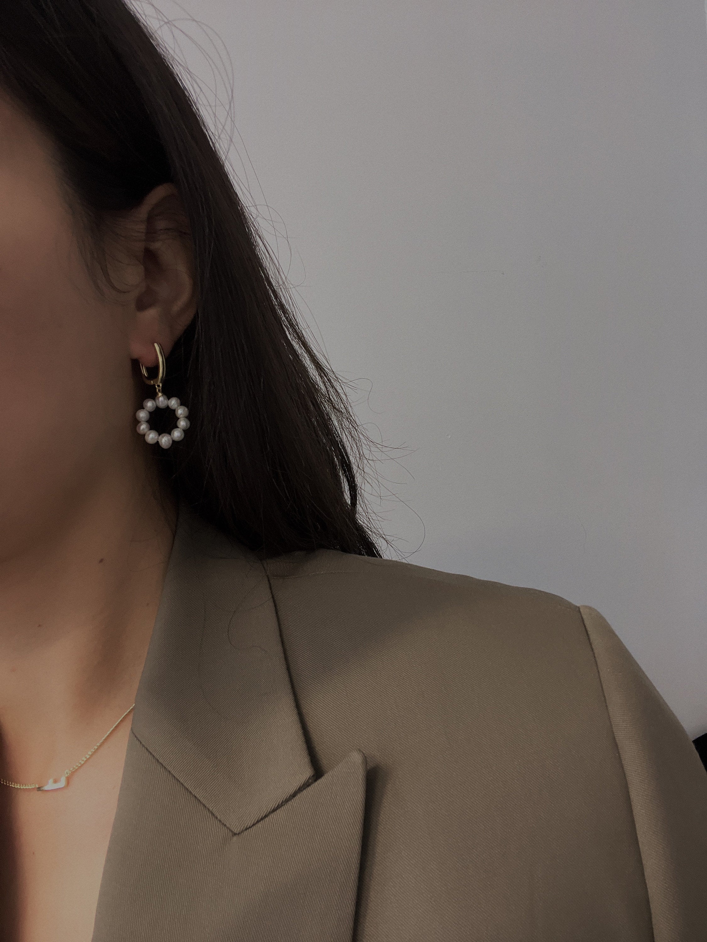 Gold-plated hoop earrings with a dangling circular ring of freshwater pearls.