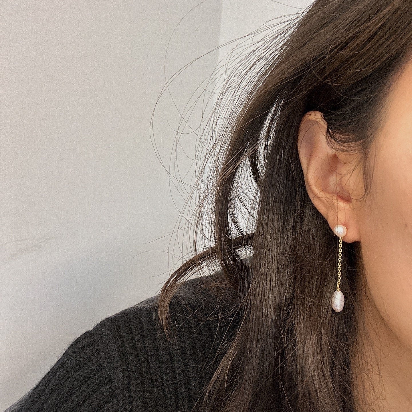 Freshwater pearl drop chain dangling earrings on a person's ear.