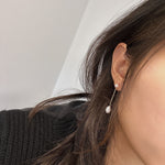 Freshwater pearl drop chain dangling earrings on a woman's ear.