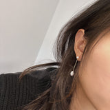Freshwater pearl drop chain dangling earrings on a woman's ear.