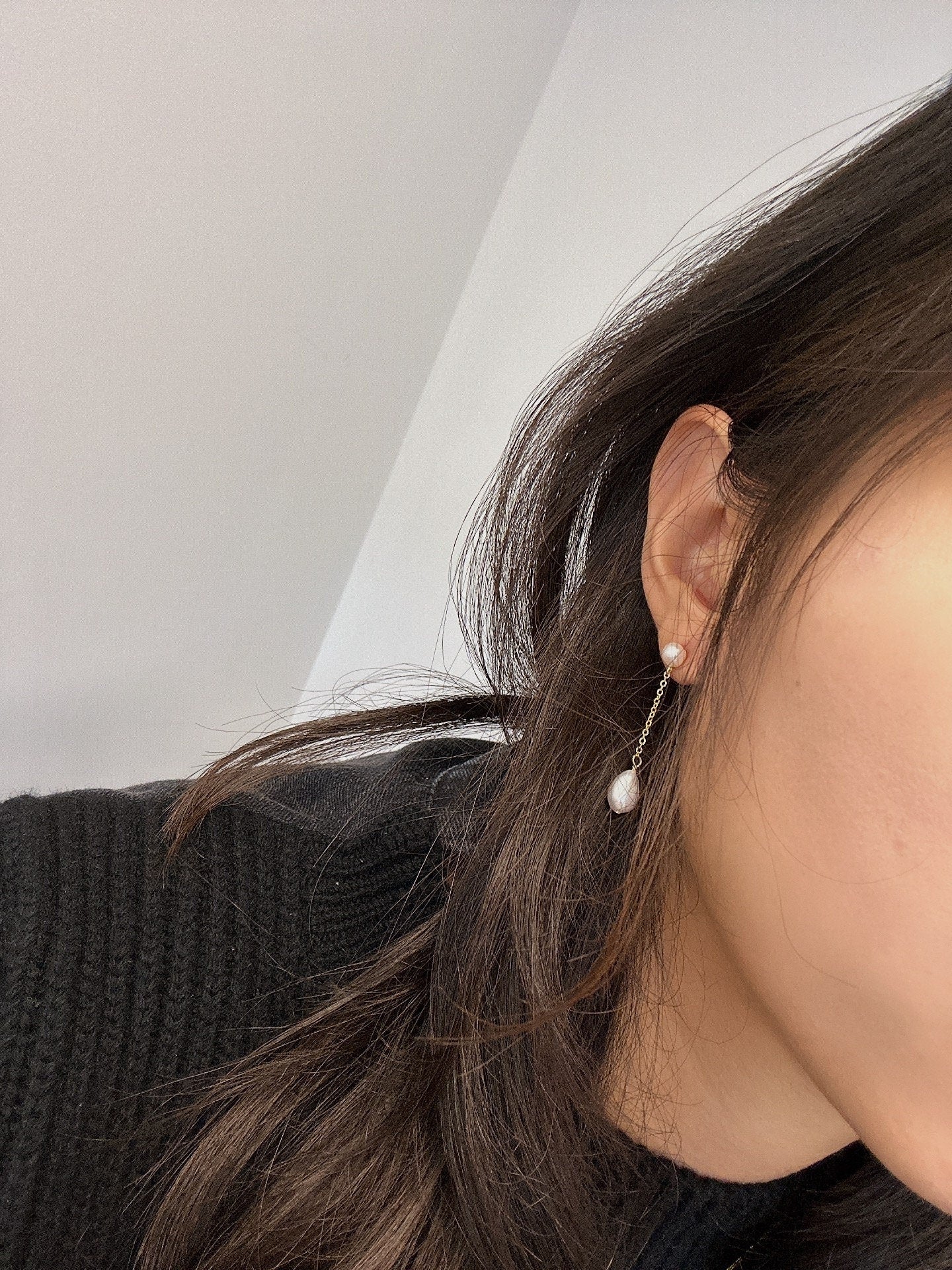 Freshwater pearl drop chain dangling earrings on a woman's ear.