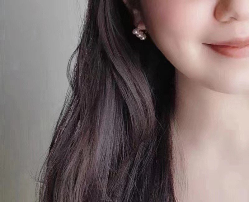 Gold-plated freshwater pearl earrings on a woman's ear.