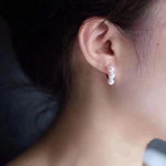 Gold plated freshwater pearl earrings with three pearls dangling from the earlobe.