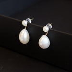 Gold plated silver earrings with two freshwater pearls, one round and one teardrop shaped.