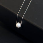 A single white pearl pendant on a delicate silver chain.