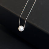 A single white pearl pendant on a delicate silver chain.