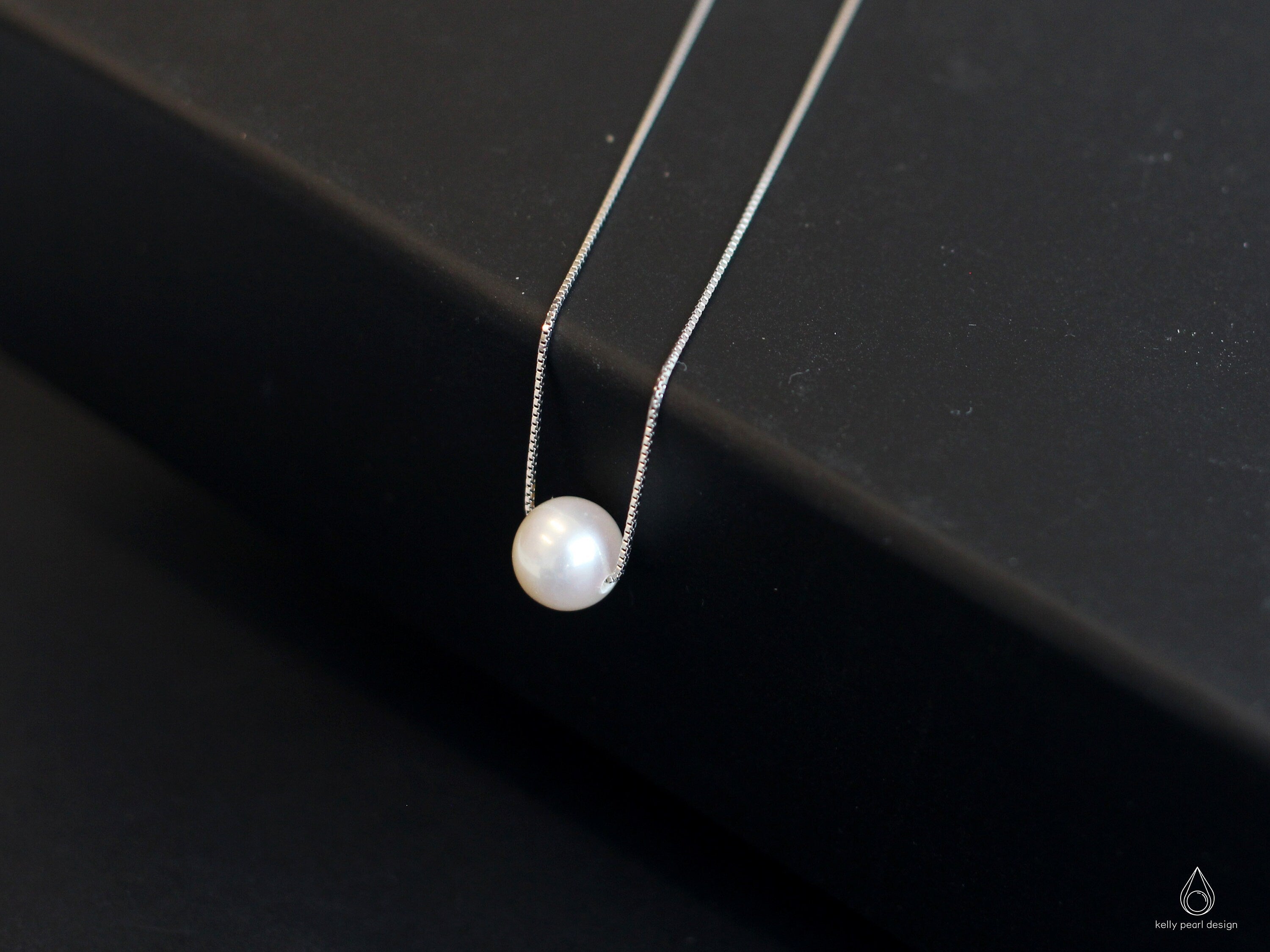 A single white pearl pendant on a delicate silver chain.