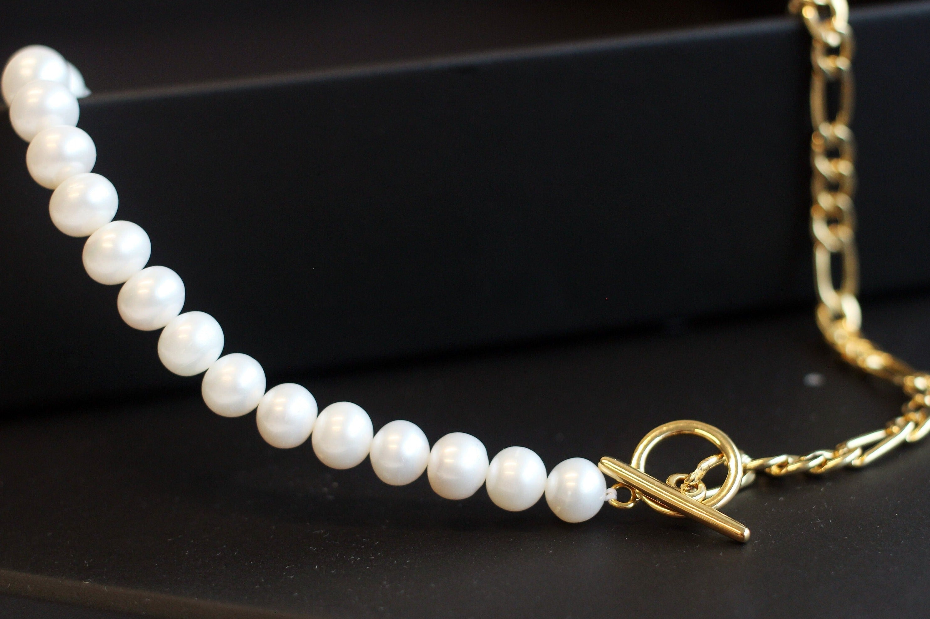 A freshwater pearl necklace with a gold-plated chain and toggle clasp.