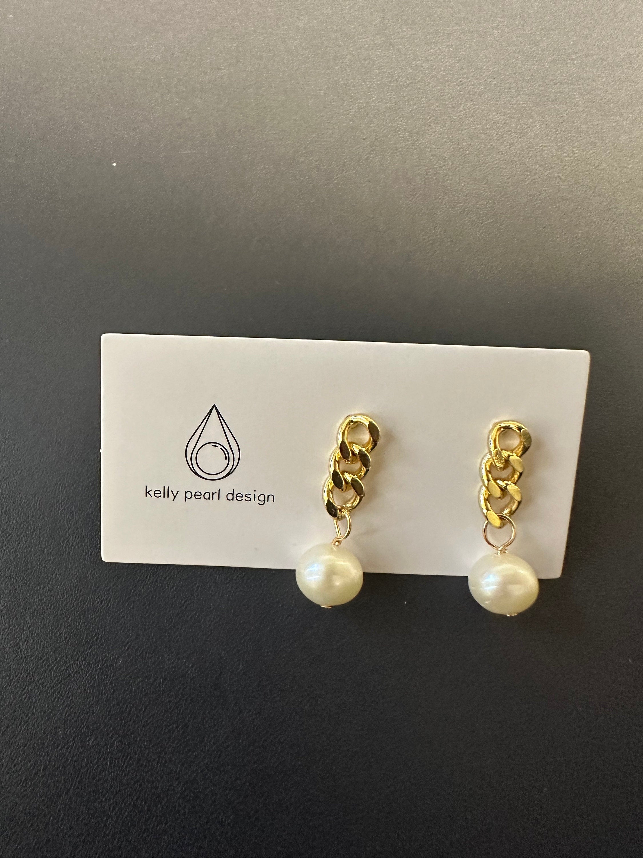 Gold chain earrings with a single white pearl drop on a white card.