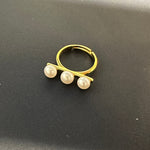 A gold ring with three freshwater pearls arranged in a line.