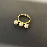 A gold ring with three freshwater pearls arranged in a line.