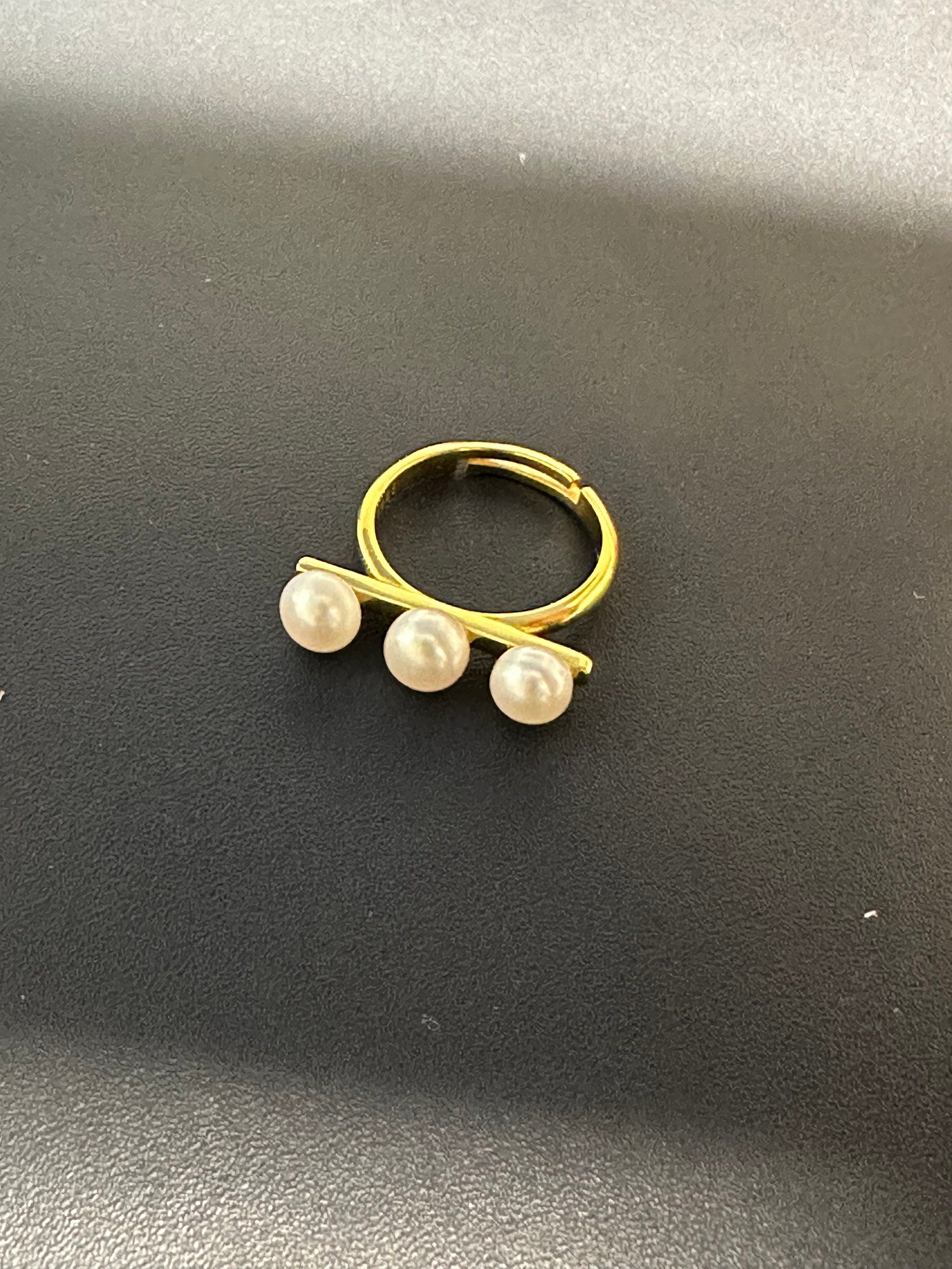 A gold ring with three freshwater pearls arranged in a line.