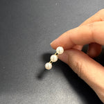 A hand holds a gold ring with three freshwater pearls.
